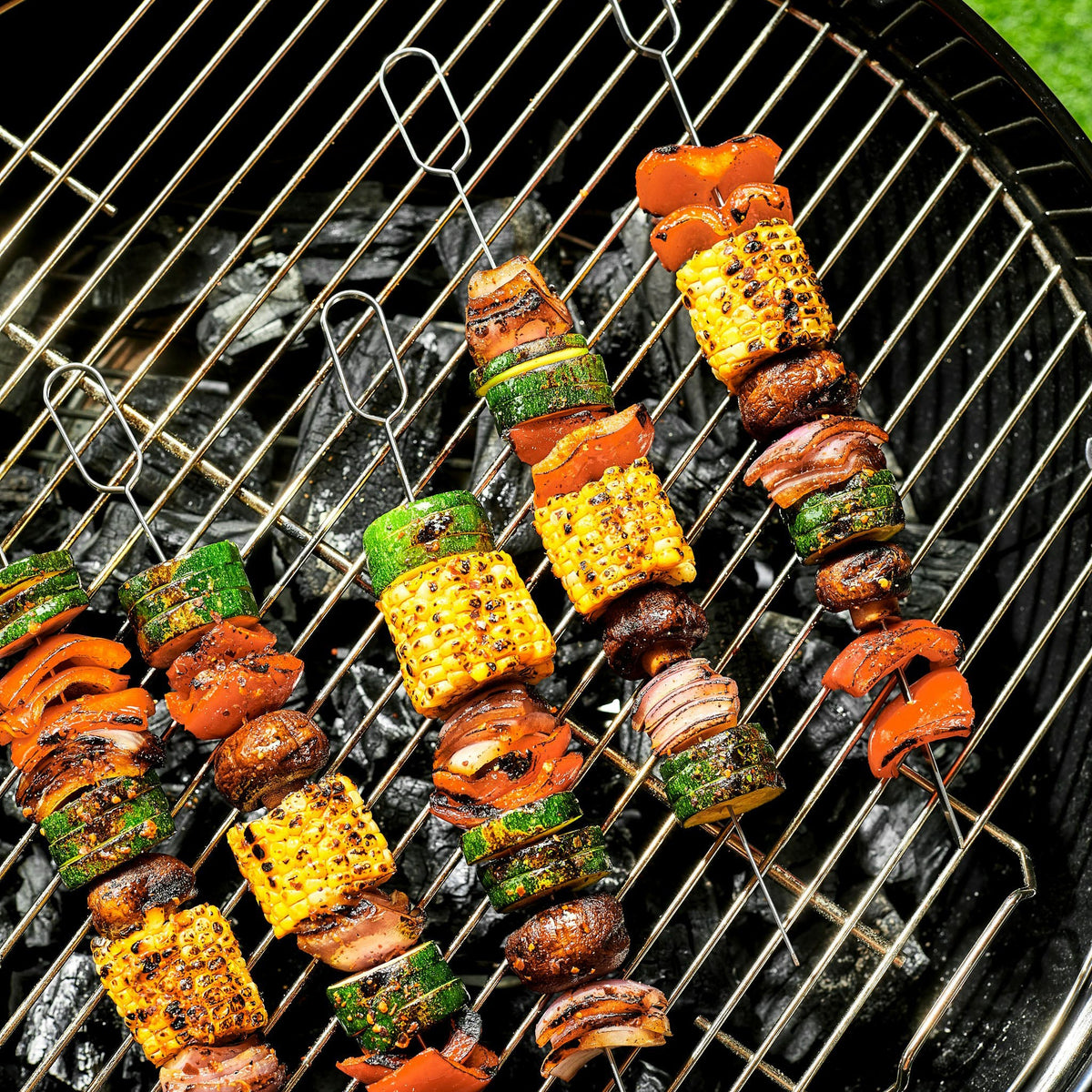 Many kebab skewers being barbecued on a grill.