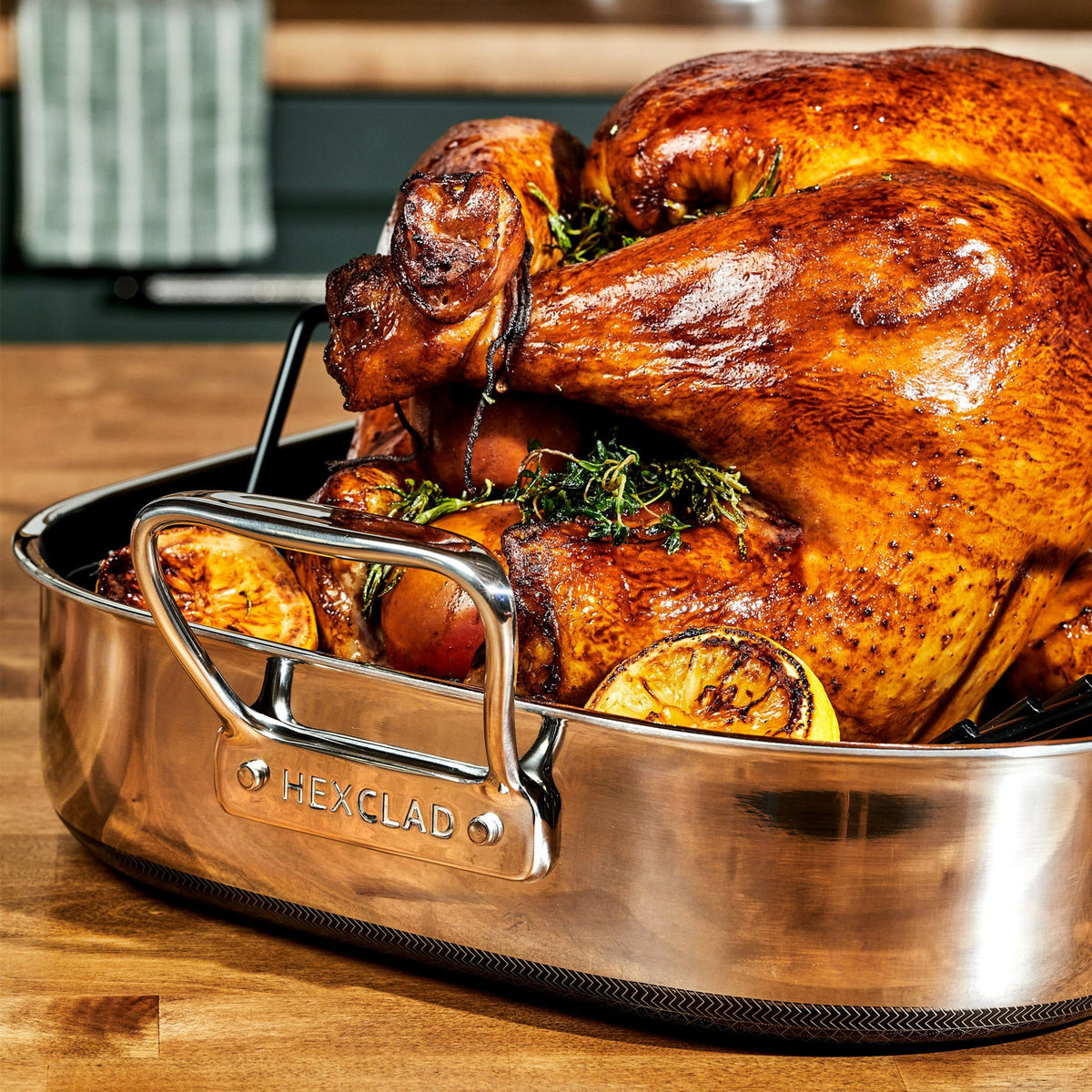 A turkey sitting inside the HexClad Hybrid Roasting Pan, along with herbs and lemon slices, after being roasted in the oven.